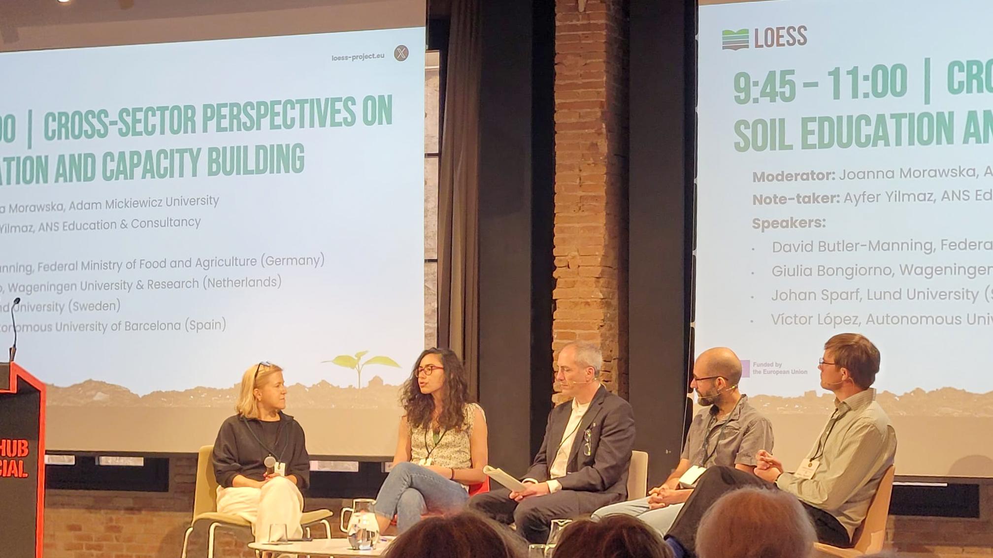Panel discussion at the LOESS symposium, with five speakers seated on stage in front of presentation slides about cross-sector perspectives on soil education and capacity building.