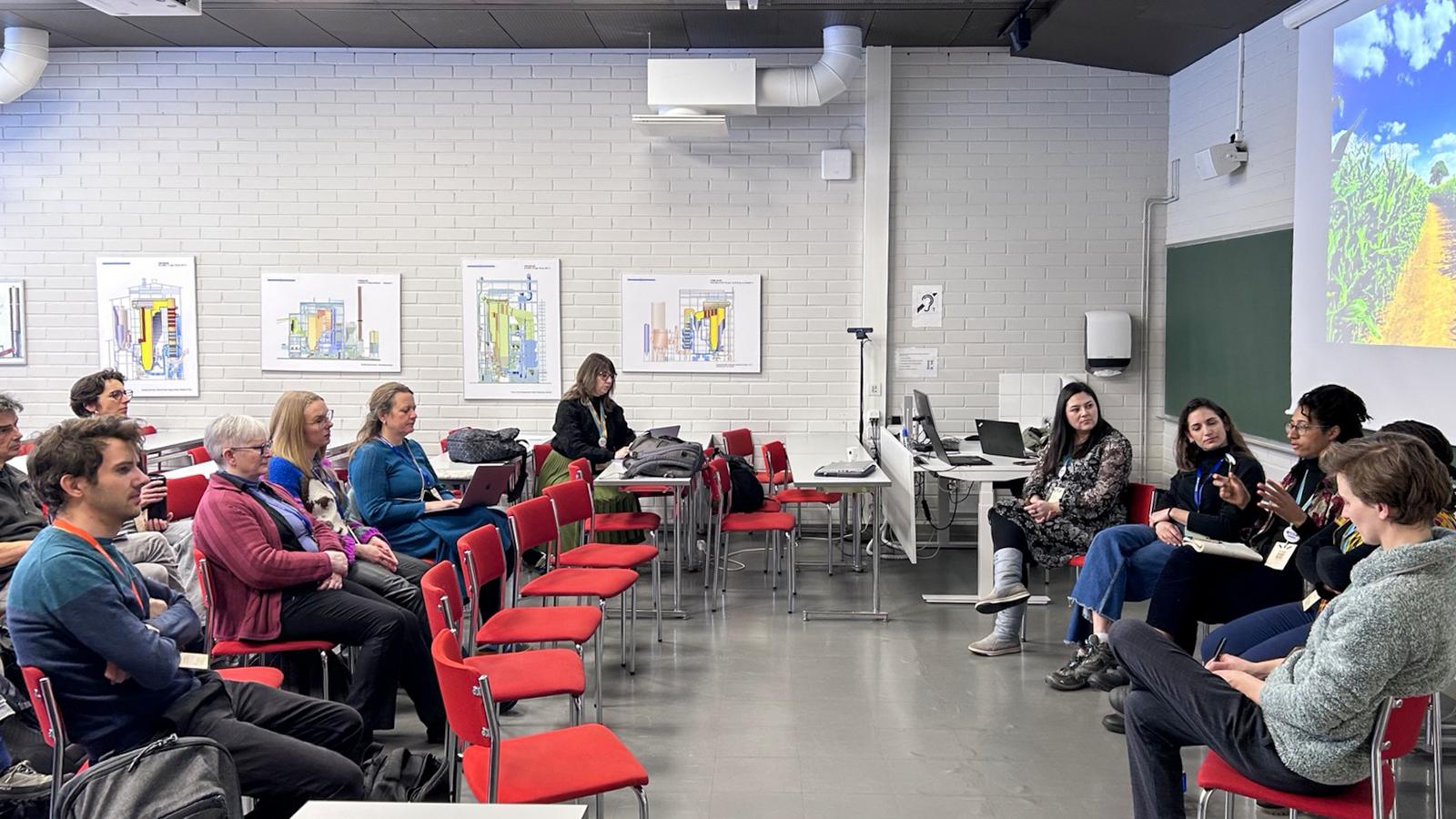 Participants sit in a classroom-style setting during the ECSA2026 panel discussion, engaging in conversation while a presentation on agricultural landscapes is projected on screen.